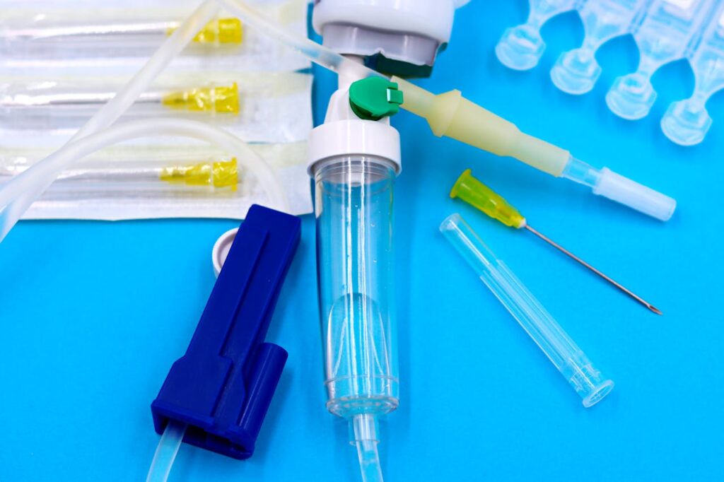 Collection of sterile medical tools including syringes and tubing against a blue backdrop.