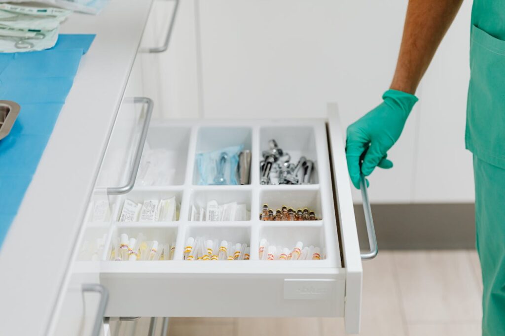Close-up of a healthcare professional opening a drawer of medical supplies in a sterile environment.